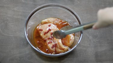 Placing chicken breast in marinade