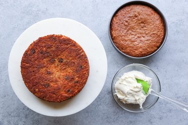 Two carrot cakes with bowl of frosting