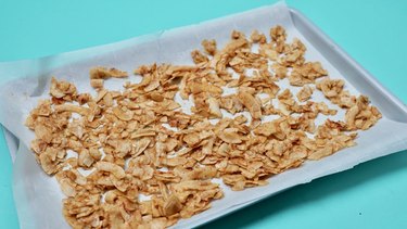 Baking coconut chips to make coconut bacon.