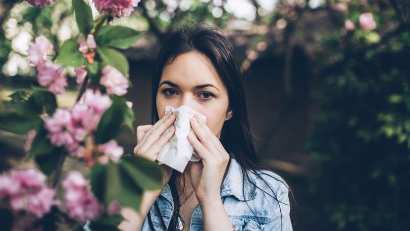 woman blowing nose around trees